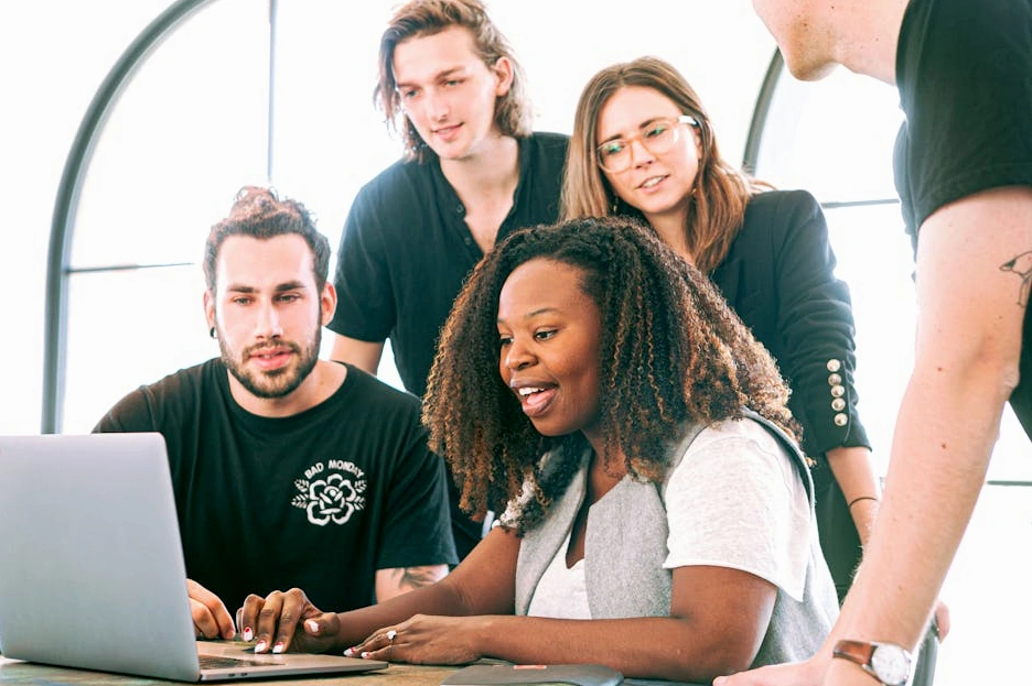 A diverse group of professionals in a modern office, collaborating around a table filled with sticky notes and sketches.